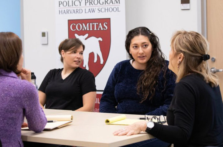Two students meet with Clinic staff at a table in the ALPP office